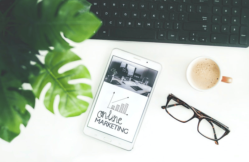 What Is Website Marketing? A work desk with glasses, a cup of coffee and a tablet saying online/website marketing