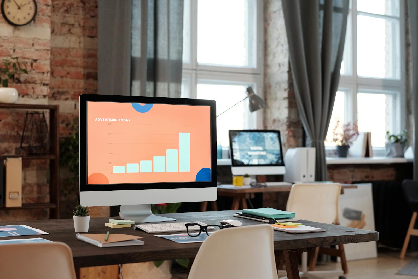 A stylish office setup featuring a computer displaying a graph on advertising trends. advertising techniques