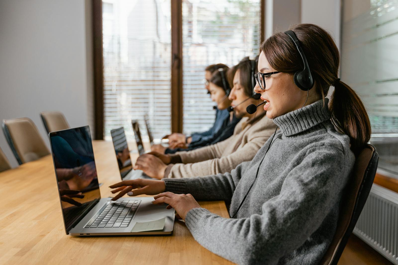 Professional customer service team working in a modern office setting with headsets and laptops. client relationship management software for small business