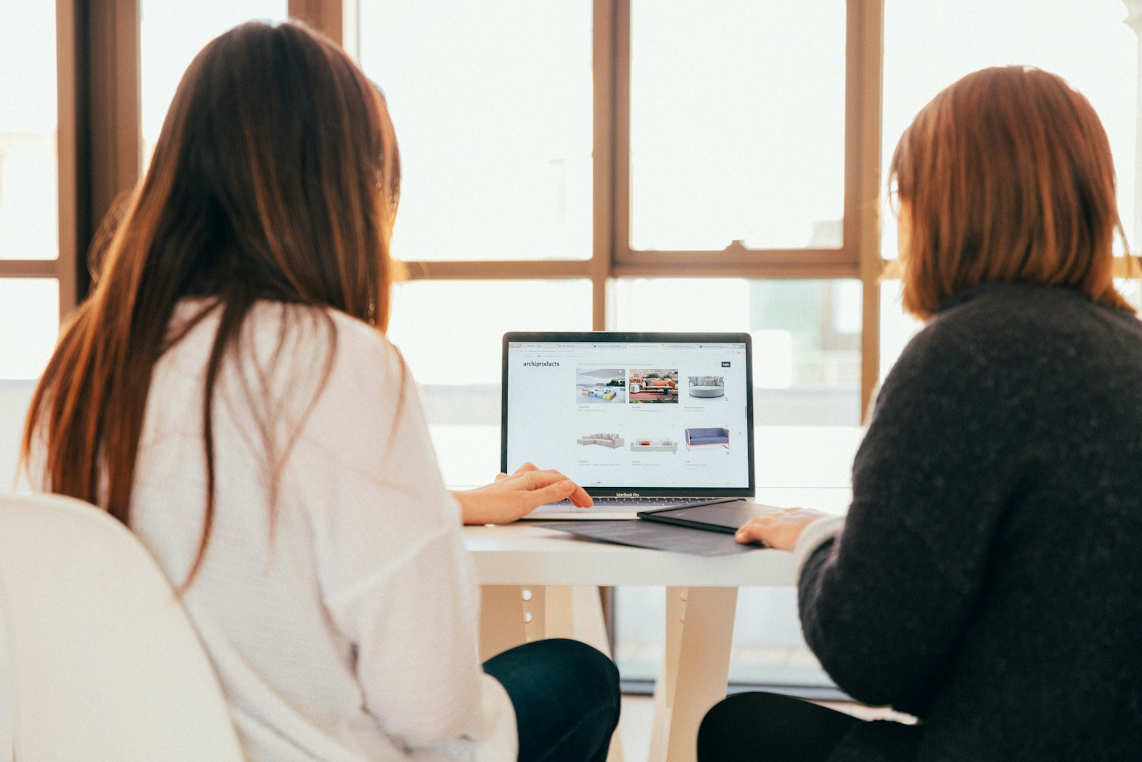 Photo by KOBU Agency two women talking while looking at laptop computer web design services for small business