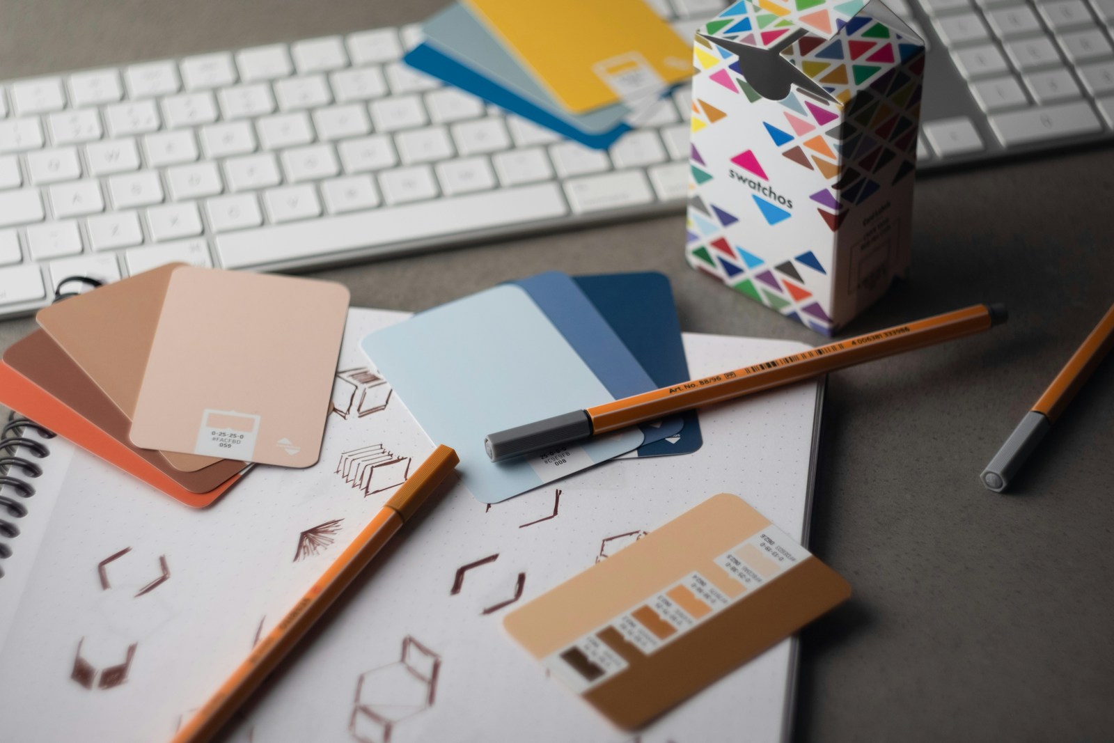 a desk with a keyboard, pencils, and various color samples 12 Proven Branding Strategies to Guide Your Business Rebrand