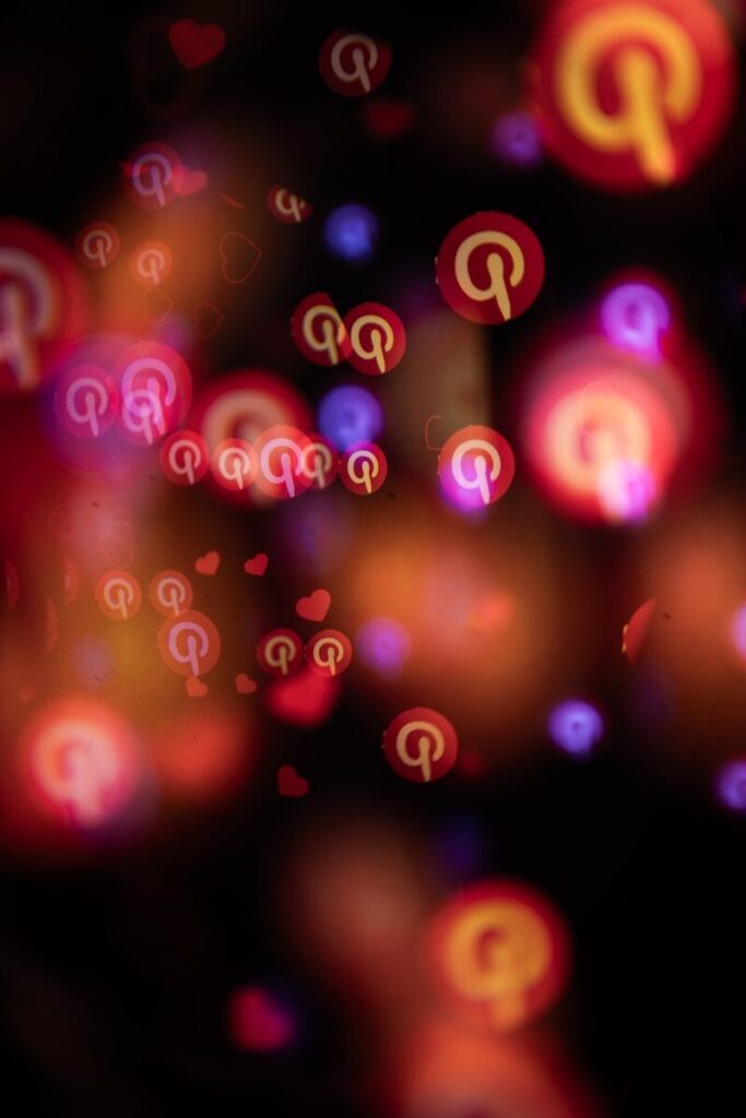 Pinterest logos and hearts float in abstract bokeh lights.
